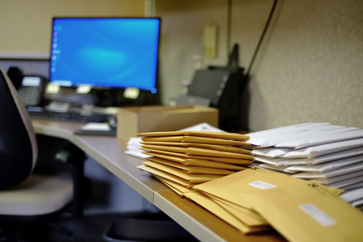 Mail stacked up on an office desk. envelopes