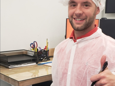 Charlotte Account Executive, Taylor Ross, wears a hair net at an on-site survey at a food plant for a local customer. He's giving the camera a thumbs up and a smile!
