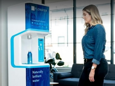 A woman stands in front of one of our Charlotte location's top sellers - a Pure Technology Flowater solution - in an office setting getting fresh water from the device.