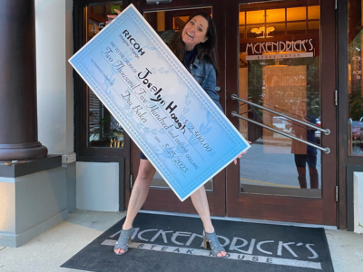 Joselyn Hough gives us a big smile holding an oversized check that was presented to her by Kelly Office Solutions' Charlotte staff on behalf of Ricoh outside of McKendrick's Steak House.