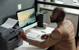 A professional working at their desk, using a multifunction device regarded as the best business printer for efficient office tasks.